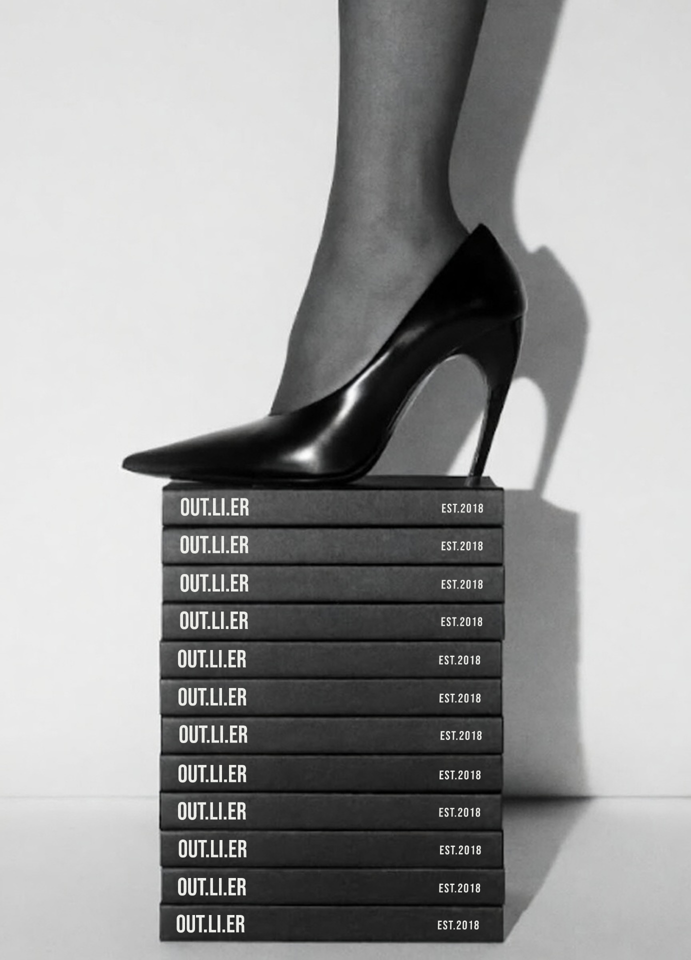 Black heel resting on a stack of OUT.LI.ER boxes